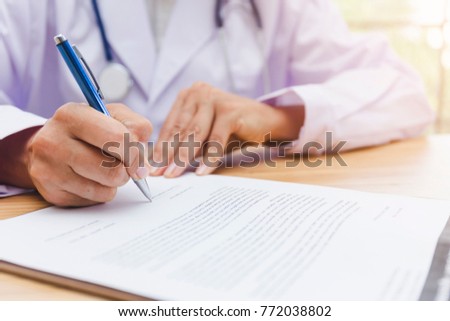Hand of female doctor is filling a prescription or signing a medical report or medical certificate or Medical examination form paperwork on office or clinic or hospital 