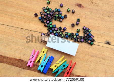 Creative layout, flat lay made of colorful wooden clip, alphabet beads and white blank board on wooden background. Reminder, notes and multi purposes concept.