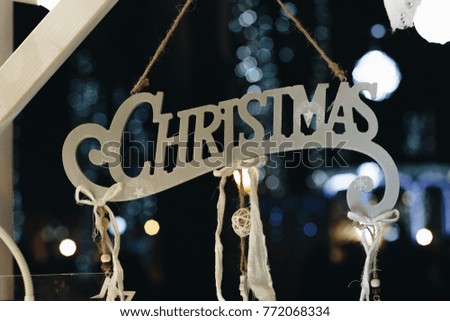 wooden sign spelling christmas hanging at a christmas market stall. bokeh background.