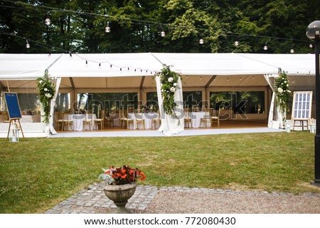 Long white tent for wedding party in the woods. Royalty-Free Stock Photo #772080430
