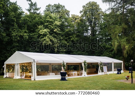 Long white tent for wedding party in the woods. Royalty-Free Stock Photo #772080460