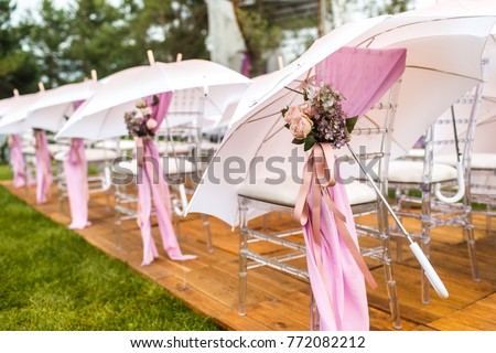 Chairs, flowers and umbrellas at an outdoor ceremony. Royalty-Free Stock Photo #772082212