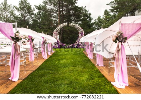 Outdoor wedding ceremony with umbrellas in the forest. Royalty-Free Stock Photo #772082221