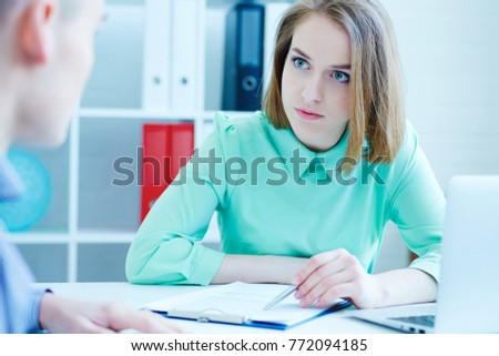 Young female employee of the staffing agency helps fill out the form to the male job seeker. Business, office, law and legal concept.