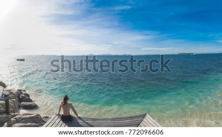 Asian woman sitting on the Wooden bridge looking at the sea.
