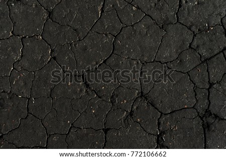 Black dried and cracked ground earth background, gray close up of dry fissure ground, grey fracture surface, dark cracked texture, for designers