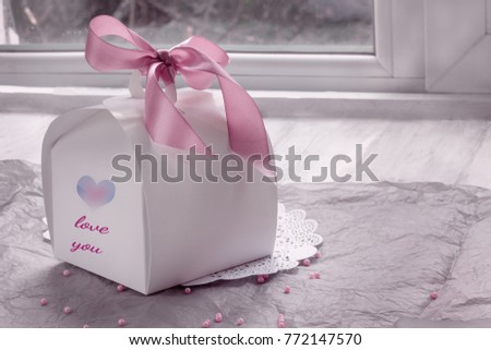 Gift white box with an inscription I love you and my heart on a wooden background with beads