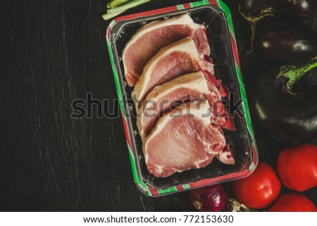 raw pork - flesh on the bone, surrounded by vegetables

