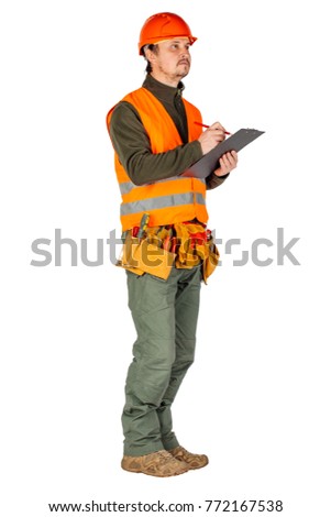male builder or manual worker in helmet writing on clipboard over white wall background. repair, construction, building, people and maintenance concept