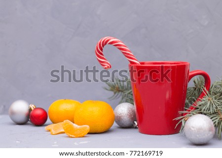 the red mug is on the table with silver and red Christmas balls, mandarins and Christmas tree tangerines
