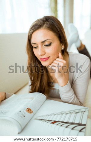 Beautiful woman on a sofa reading a paper in the living room