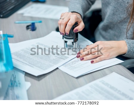 girl puts a stamp on documents in the office Royalty-Free Stock Photo #772178092