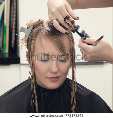 Picture showing hairdresser holding scissors and comb close up hairdresser cutting hair a woman in.