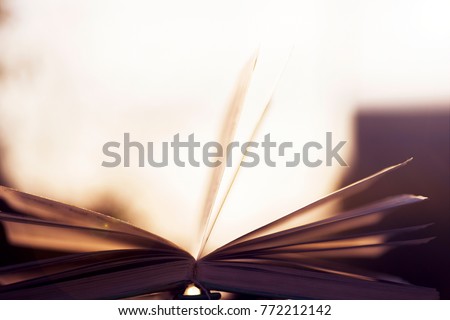Open book on wooden table on natural background. Toned image. Soft focus