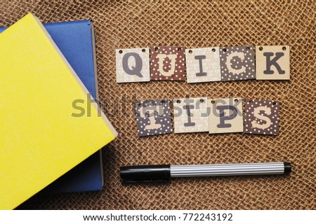 Quick Tips Concept.Book, pen and alphabet blocks with QUICK TIPS inscription on vintage canvas sack background.