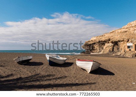 Three boats in Ajuy Fuerteventura Black Sand beach with caves and palm tree shaped shade