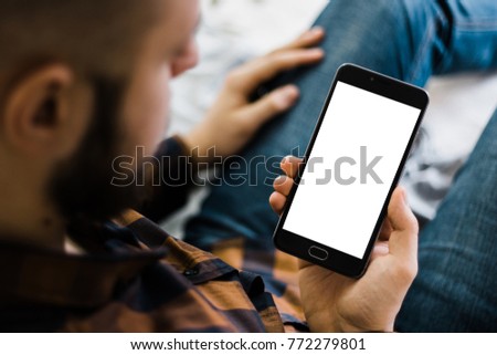 Young bearded hipster holding a smartphone in the hands of a white screen, holding mobile smart phone with chroma key mockup new technology concept Royalty-Free Stock Photo #772279801
