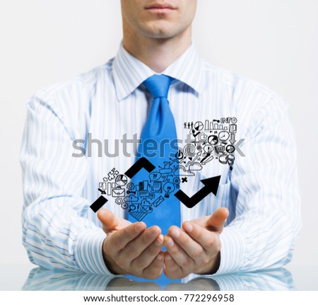Businessman in suit sitting at desk making protective gesture with palms