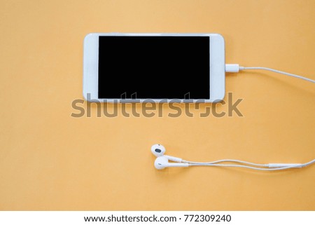 Earphones and Smartphone on Orange Background Top View