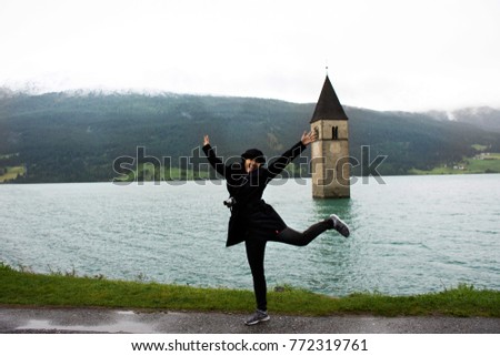 Traveler asian thai woman travel and posing for take photo at Submerged tower of reschensee church deep in Resias Lake in Trentino-Alto valley or Alto Adige in Bolzano or bozen city at Italy