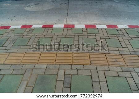 Asphalt road and Concrete block sidewalk with Red and white concrete curb