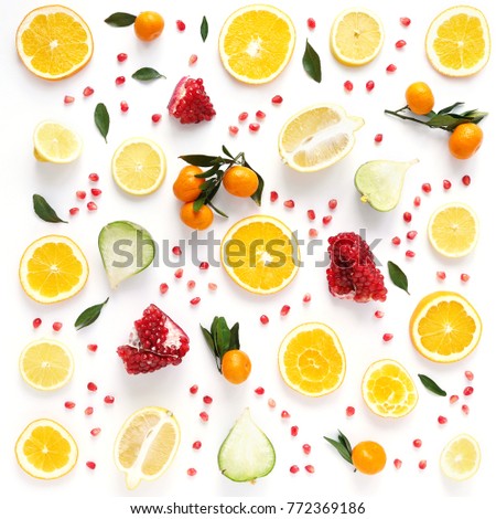 Creative flat layout of fruit, top view. Sliced orange, lemon, pomegranate, tangerine, green leaves isolated on white background. Food wallpaper, composition pattern of fresh fruits.	