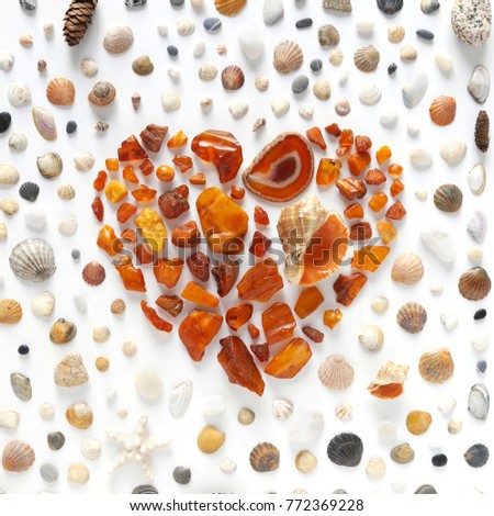 A creative pattern of shells, unprocessed pieces of amber, natural stones, starfish. Composition of natural materials, flat lay, top view. Heart made from stones of amber, cut of agate and shell.