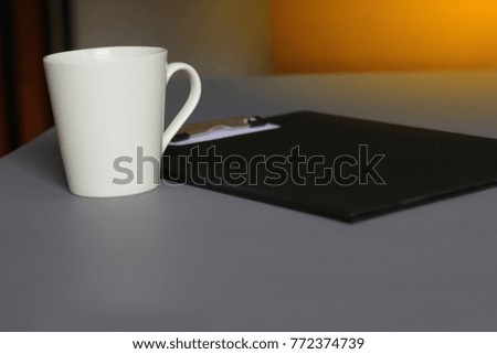 A beverage glass and black clipboard on the table.