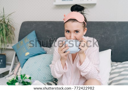 Portrait of young happy woman drinking morning coffe or tea in the bedroom  Royalty-Free Stock Photo #772422982