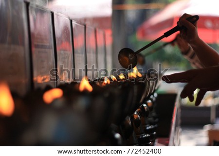 Buddhist people poring water and Candle fuel on to sacred flame, Buddhist ritual, Sacred flame in Buddhist temple