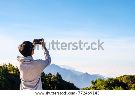 man is shooting video of beautiful mountain on cell telephone, while is standing against Amazon scenery background with copy space. Male tourist is taking photo with mobile phone camera