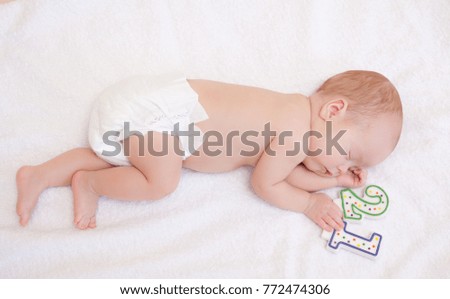 Picture of newborn baby lying in bed on white towel with candle