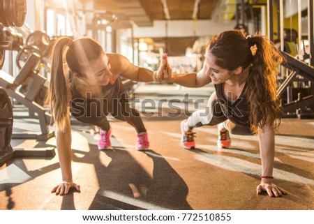 Sporty women giving high five to each other while working out together at gym. Royalty-Free Stock Photo #772510855
