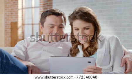 Excited wife and husband looking at tablet, shopping online, family business