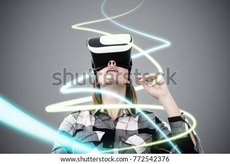 Portrait of a young woman in a checkered shirt wearing VR glasses and looking upwards. A gray background. Curved lines of light. Toned image double exposure