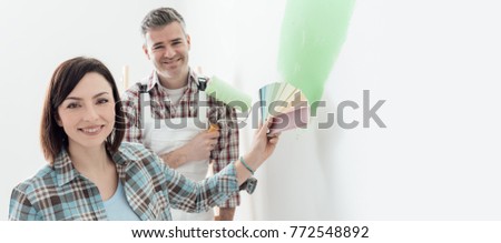 Woman choosing the perfect paint color for her room with a professional painter and decorator, she is holding color swatches