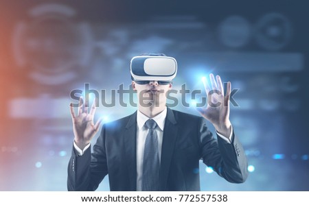 Portrait of a young businessman wearing a suit and VR glasses and interacting with what he sees. A blurred background. HUD. Toned image double exposure