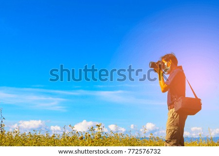 young man photographer taking photos on the mountain with blue sky background