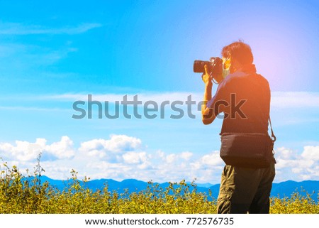 young man photographer taking photos on the mountain with blue sky background