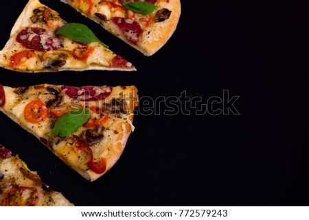 Hot and delicious pizza slices ready to eat on a black wooden background