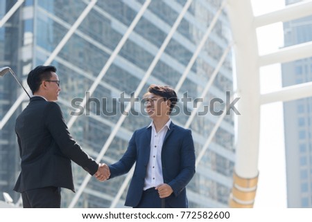 businessman in hand holding golf equipment being handshaking in the background of city building office. Business deals concept