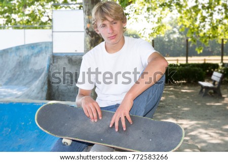 young blond boy man with skateboard in town
