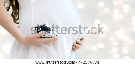 Pregnant woman belly holding  ultrasound scan of baby. Healthy pregnancy. Newborn baby booties in parents hands. Concept of Pregnancy health care.