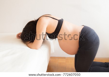 Pregnant woman having contractions in labour pain  Royalty-Free Stock Photo #772607050