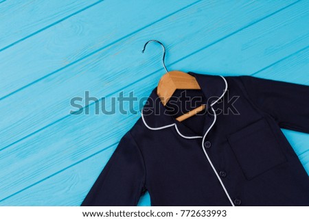 Shirt on wooden hanger. Navy garment with breast pocket and rounded collar. Fashion clothing background.