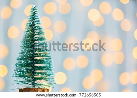 A Christmas tree on the background of a bokeh glowing garland and white boards. Merry Christmas, ideas for postcards for winter holidays
