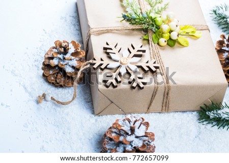 Christmas frame with gift, the branches of the Christmas tree and wooden decorations on snow background. Simple Christmas composition with free space