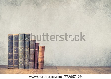 Vintage old books on wooden table front concrete wall background. Retro style filtered photo
