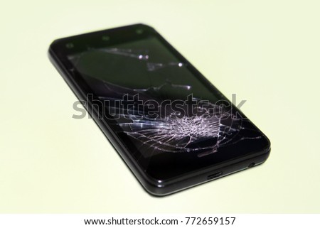 black Smartphone with broken screen on a green background