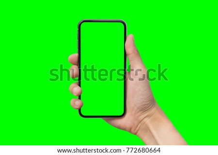 Man's hand shows mobile smartphone with green screen in vertical position isolated on green background. Mock up mobile